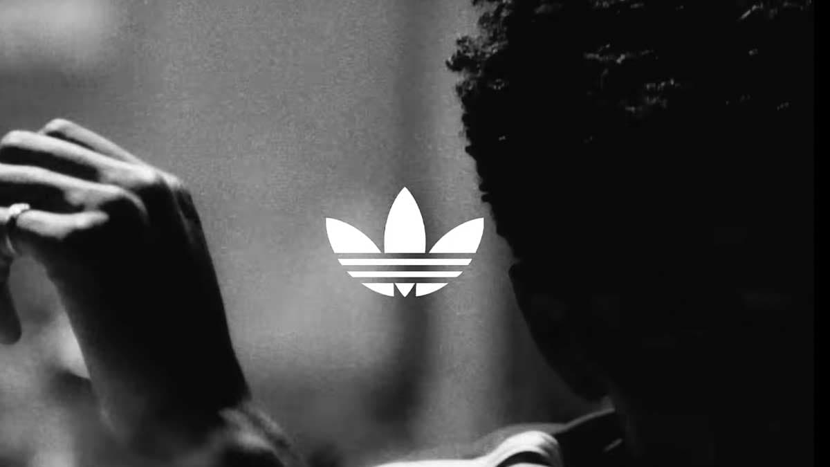 A black and white photograph of a raised arm beside the adidas trefoil
