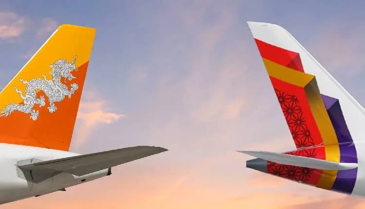 The tail fins of a Drukair aircraft carrying the Bhutan dragon emblem and an Air India aircraft, against a sunset sky